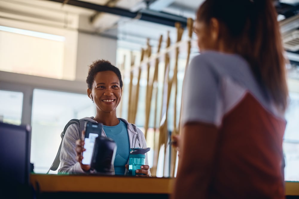 Athlete using a smart phone and scanning her QR code while checking in at gym