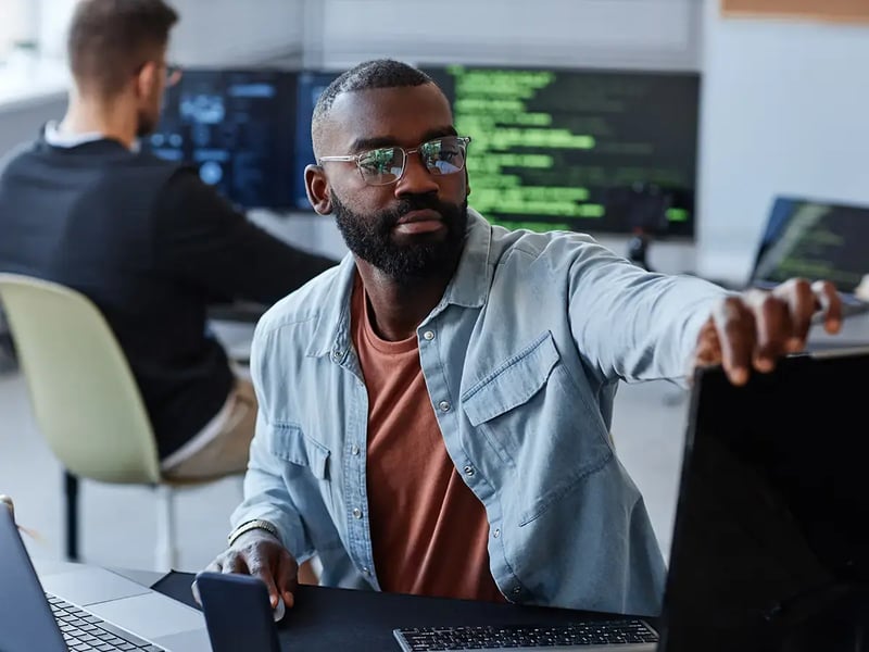 A man in glasses and casual attire works in a modern office