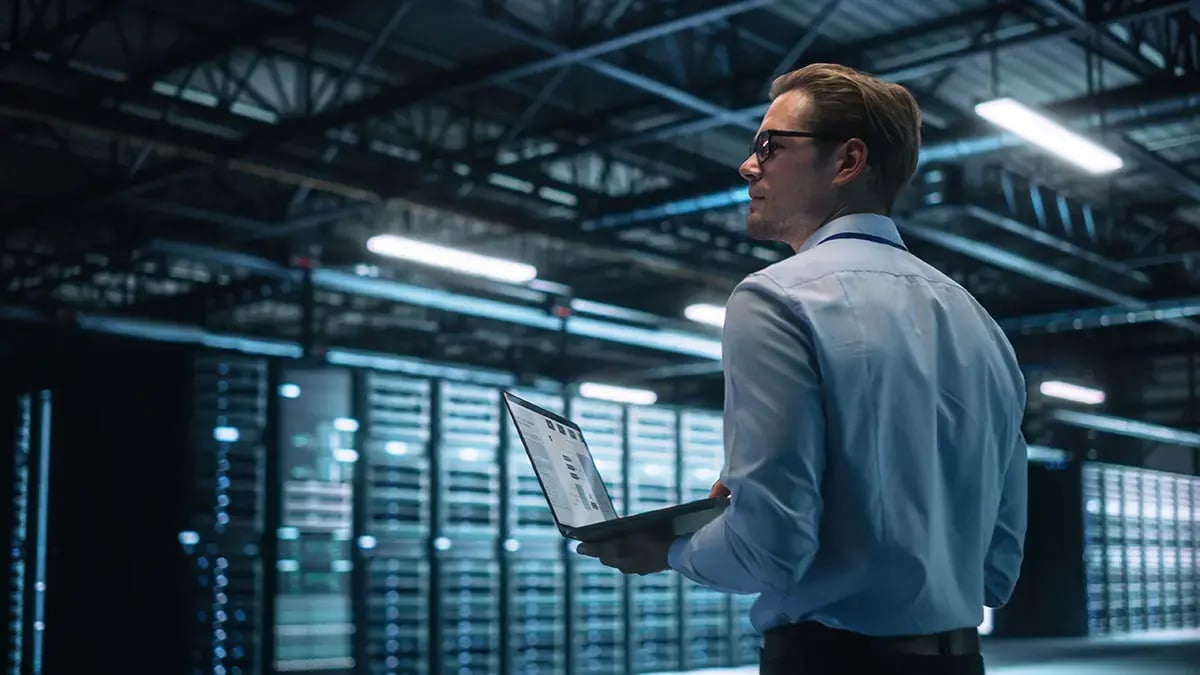 Man holding computer in a server room