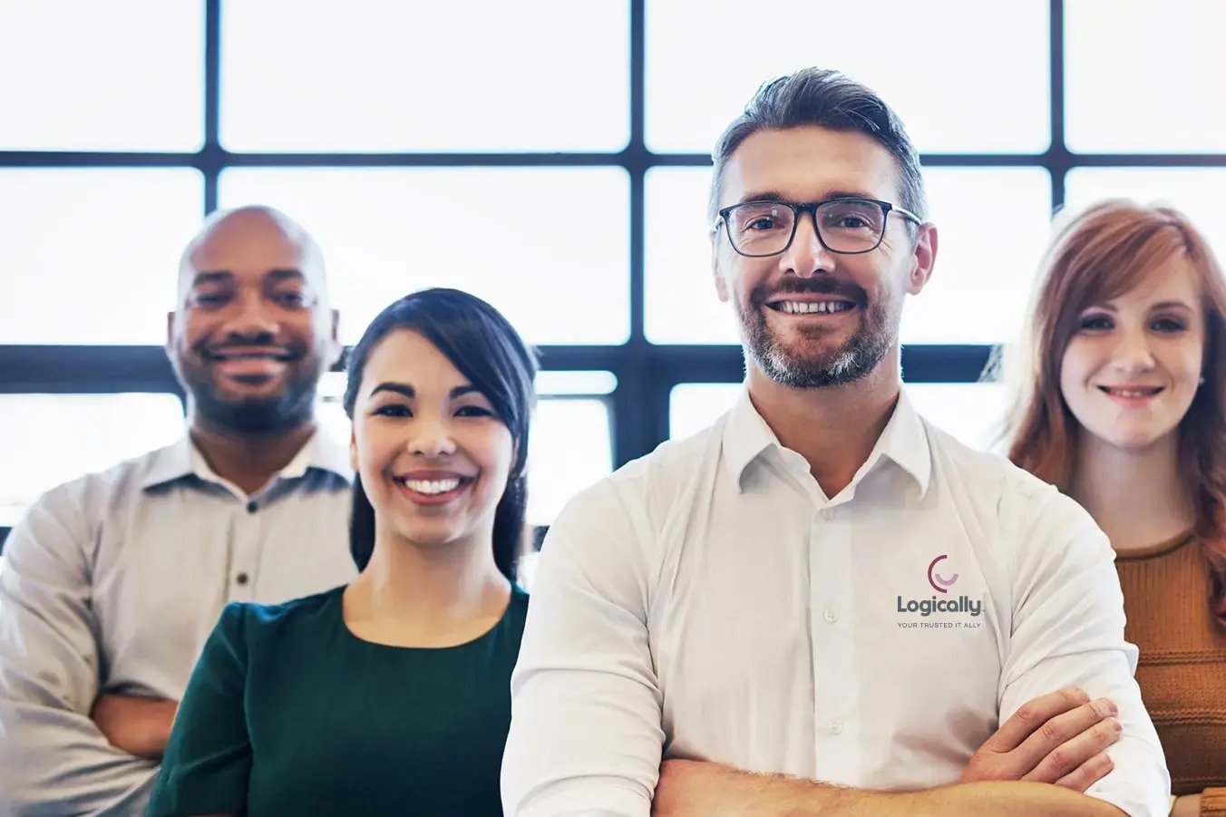A diverse group of four smiling professionals stands together in an office.