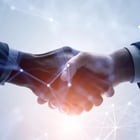 Two hands shaking with a digital network overlay.