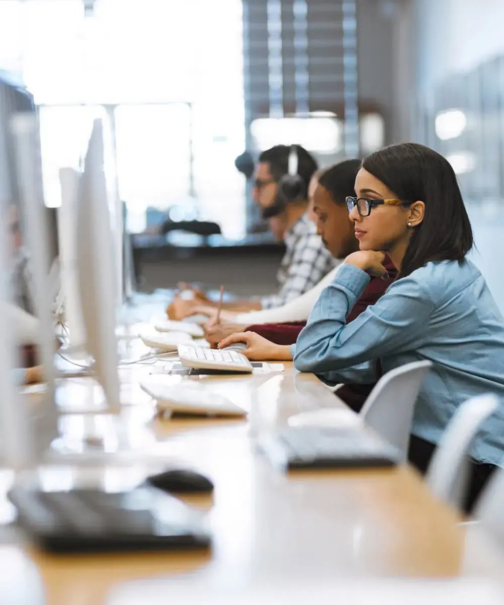A focused group of diverse professionals working at computers in a modern office.