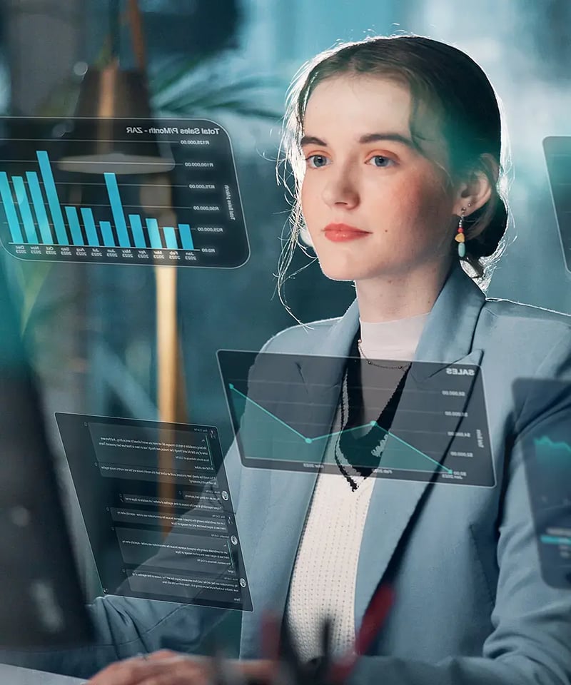 A woman in a blue suit looks at floating digital graphs and charts.