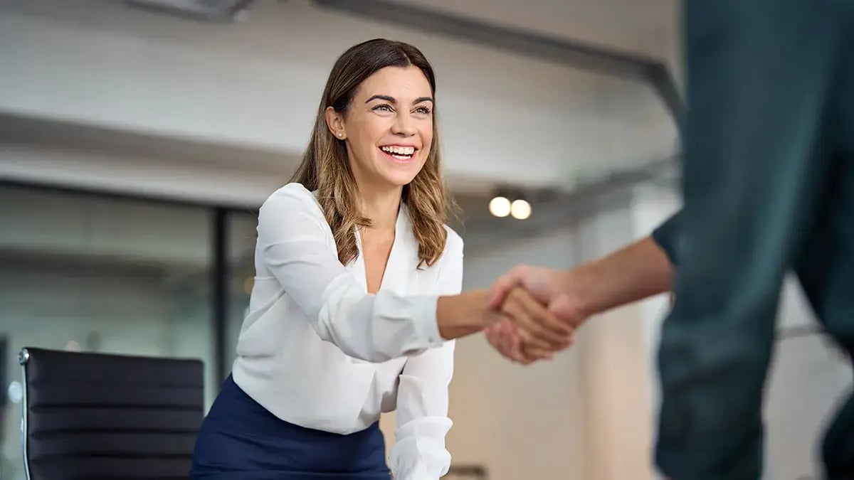 A woman shaking hands with a client.
