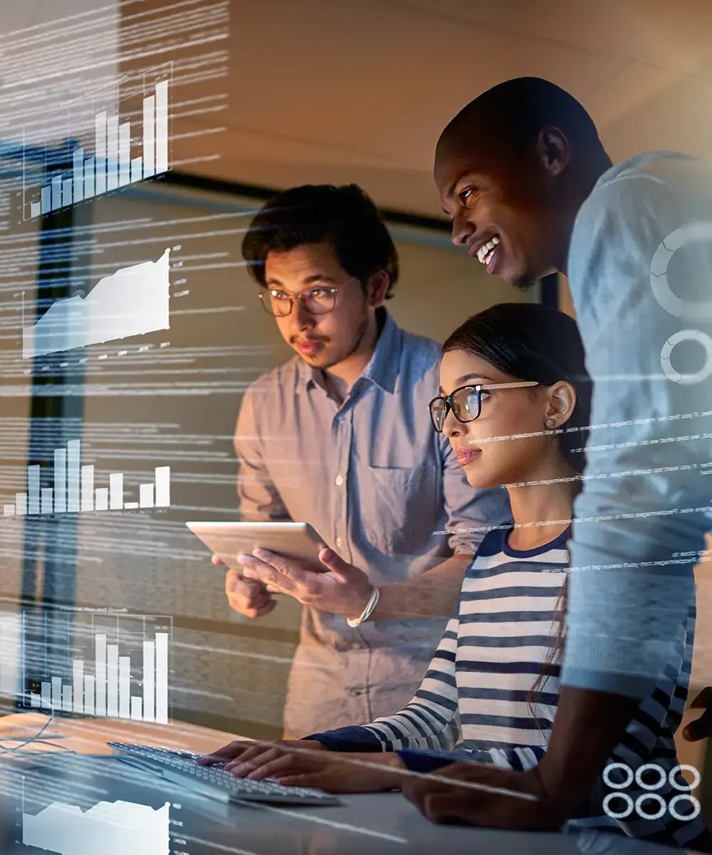 A diverse group of three focused professionals analyzes futuristic digital graphs on a transparent screen, reflecting teamwork and innovation.