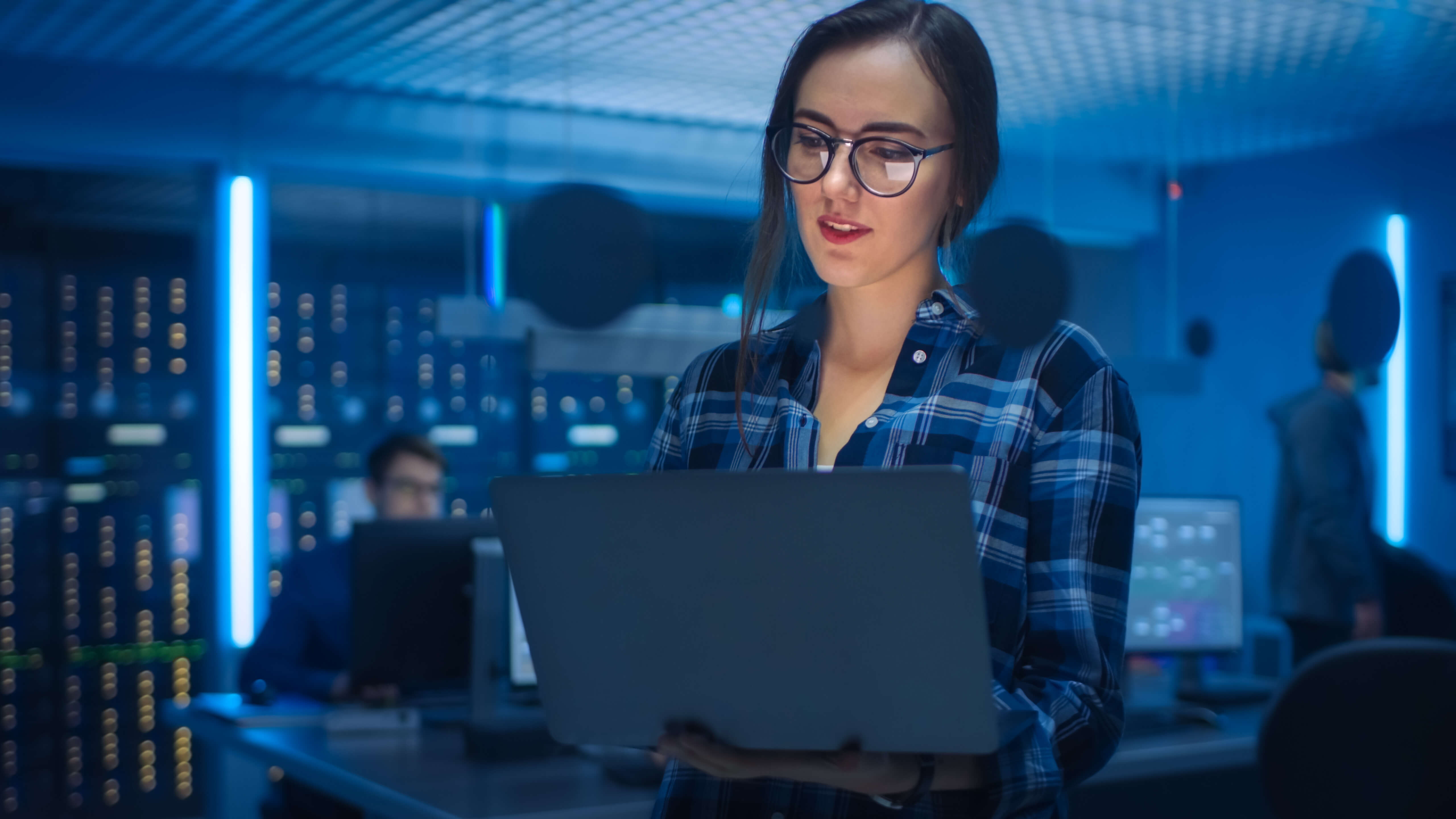 Woman looking at laptop screen standing in server room