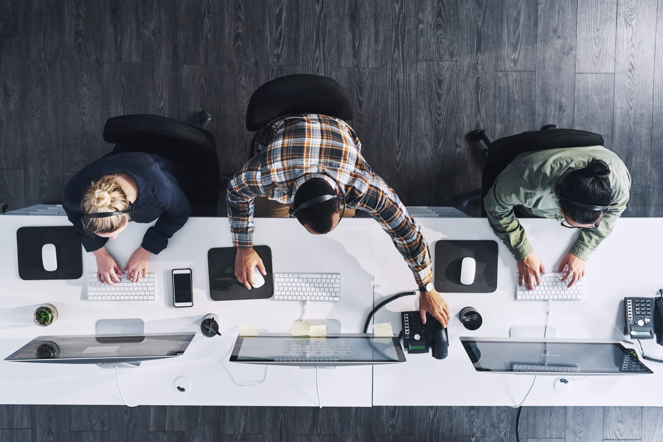 view of three people sitting in their desks at an office from above