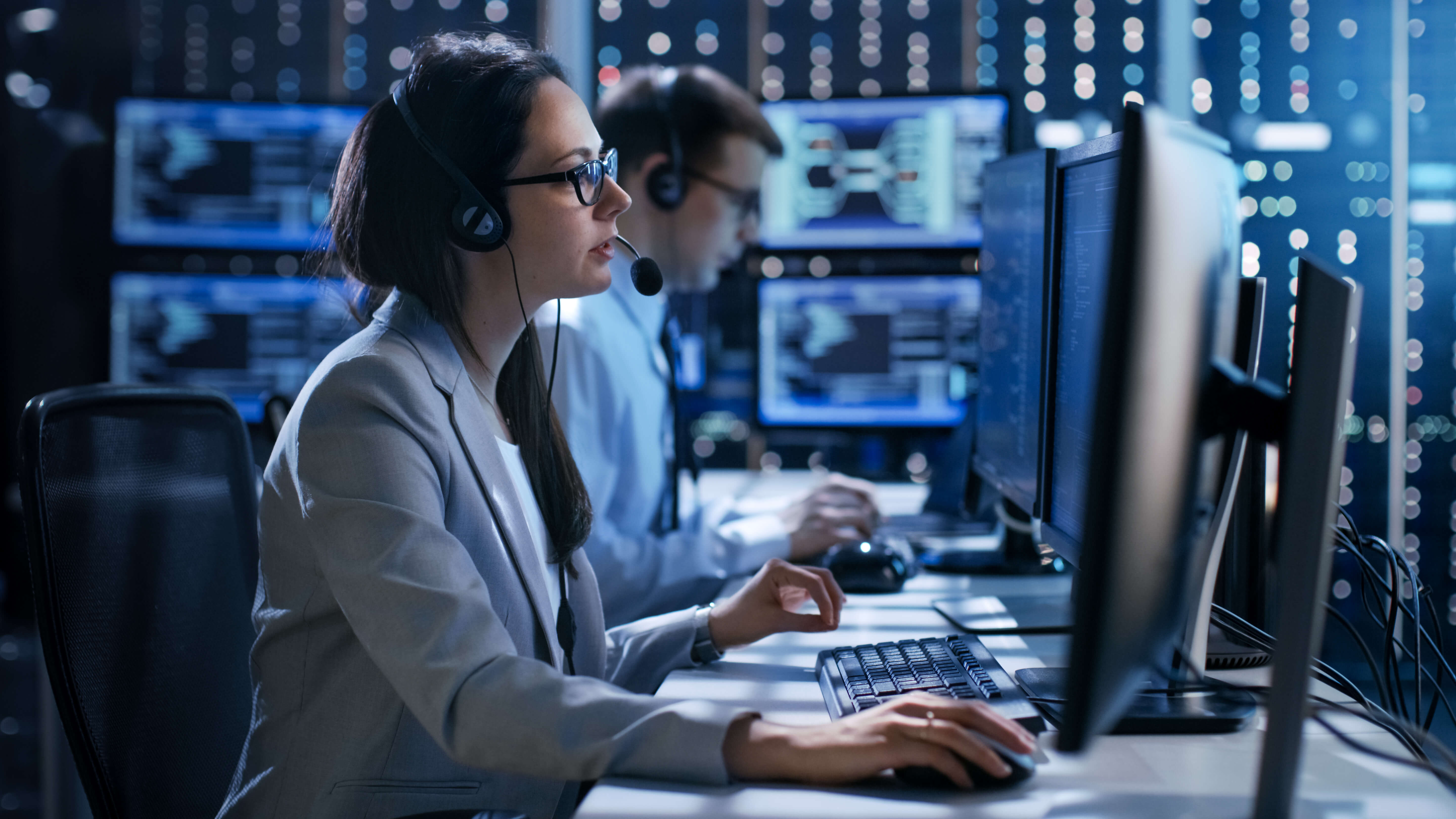 Woman working in her computer answering a call wearing headsets