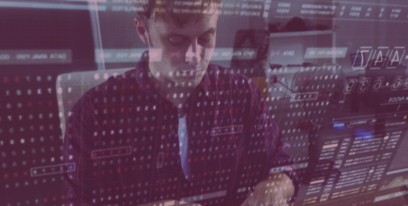 A man's face and desk are reflected in the screen of his monitor, where he is actively working on a technical project
