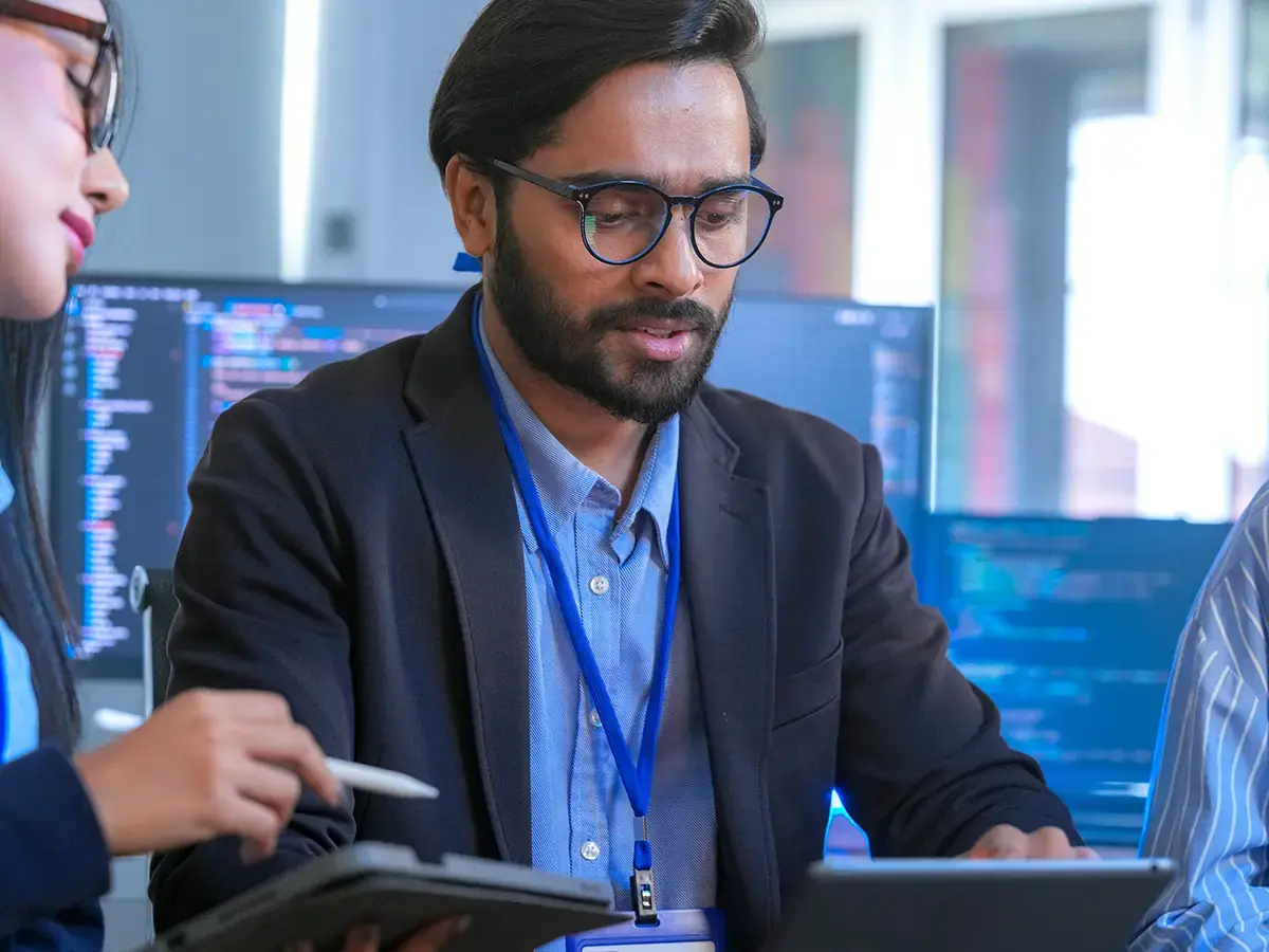 A team collaborates in an office with coding screens in the background
